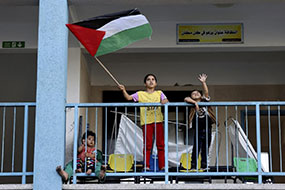 Palestinian children hold flag at refugee site